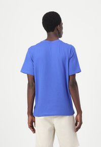 Kurzarm-T-Shirt aus lebhaft blauem Baumwollstoff, mit Rundhalsausschnitt und lockerer Passform. Die Rückansicht zeigt eine glatte Textur und ein sauberes Design.