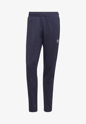 Granatowe dresowe spodnie marki Adidas z elastycznym pasem, przednimi kieszeniami na zamek błyskawiczny oraz logo Adidas na górnej części uda.
