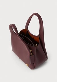 Maroon leather handbag with a smooth texture, dual short handles, and a gold hardware tag. Interior showcases a contrasting brown lining.