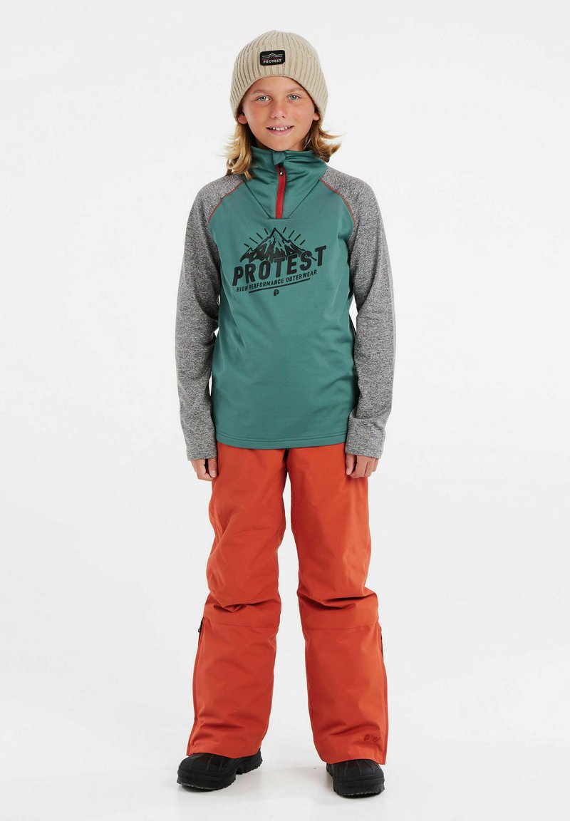 Fleece leggero color teal con mezza zip e maniche grigie, caratterizzato da una grafica di montagne e dalla scritta "PROTEST". Abbinato a pantaloni da neve arancioni e stivali neri.