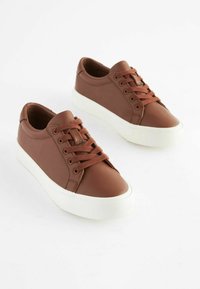 Brune lædersneakers med hvide gummisåler, runde tæer og snørebånd foran. Tekstureret overflade med diskrete syninger.