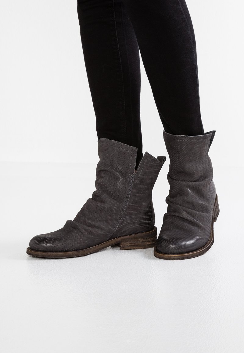 Bottes de cheville grises avec une finition texturée, un design décontracté et une large ouverture en haut. Le talon en bois robuste ajoute un contraste au matériau.