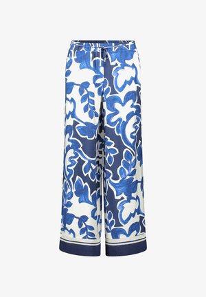 Bukser med vide ben i hvidt stof med dristige blå blomsterprints. Elastisk linning med snøre og marineblå kant forneden.