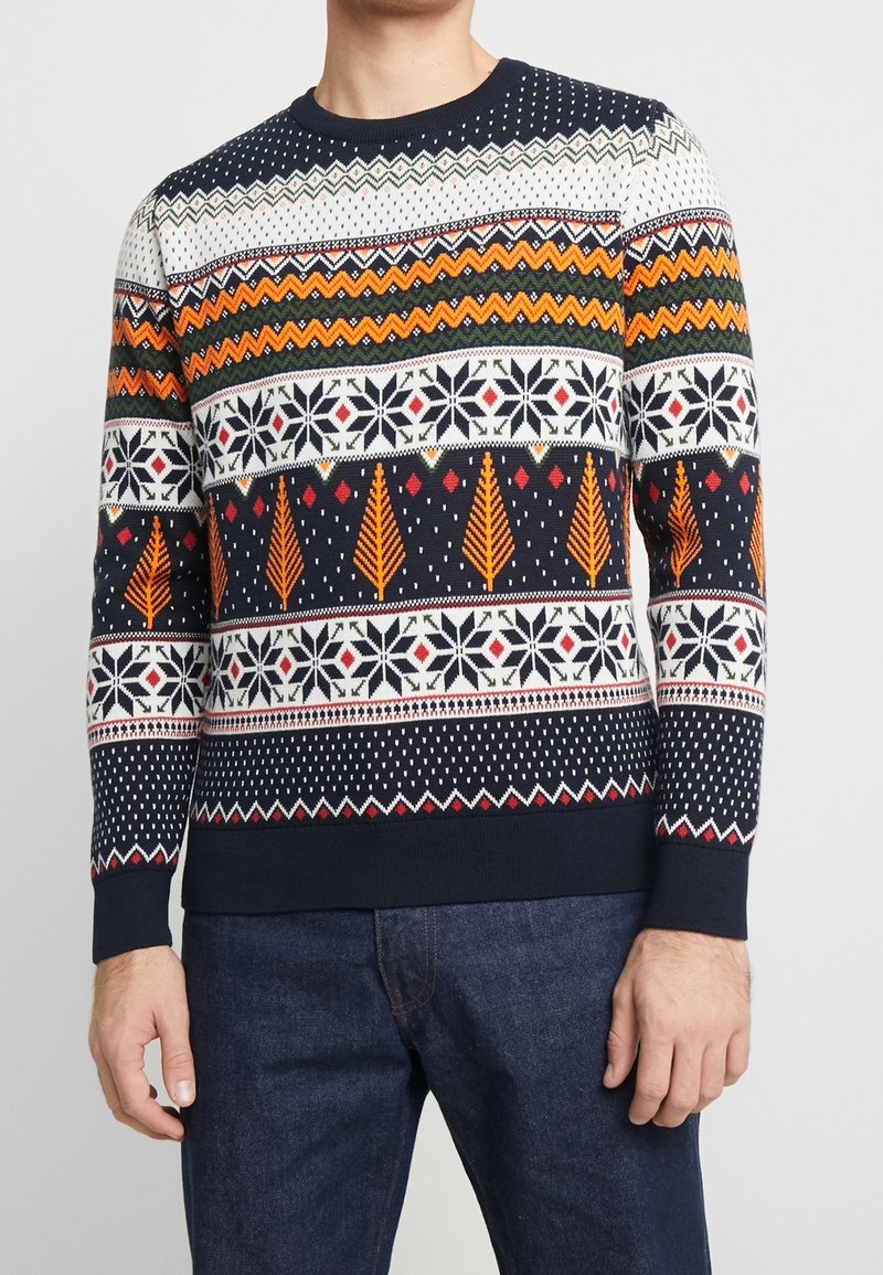 Stickad tröja med marinblå bakgrund och multicolor geometriska och trämönster i orange, vitt och grönt. Ribbade muddar och nederkant.