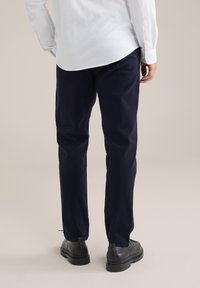 Tums tumši zilā krāsā, izgatavoti no viegla auduma, ar taisnu griezumu, jostu un smalkām šuvju detaļām, kombinēti ar melniem apaviem.