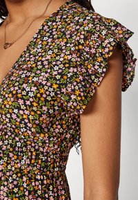 Abito floreale nero con maniche a volant, vita aderente e un mix di fiori rosa, arancio e bianchi su uno sfondo scuro.