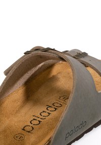 Sandalo grigio in suede con soletta in sughero, dotato di una fibbia metallica regolabile. La superficie interna è morbida e leggermente testurizzata, contraddistinta dalla scritta "palado."