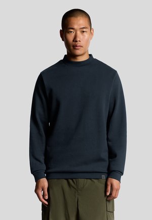 Felpa navy con collo alto e maniche lunghe, realizzata in un tessuto morbido. Presenta polsini a costine e una discreta etichetta logo sull'orlo.
