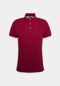 Burgundin värinen polo paita, joka on valmistettu pehmeästä kankaasta ja jossa on kolmen napin lista, lyhyet hihat ja pieni logo korostus vasemmassa rinnassa.