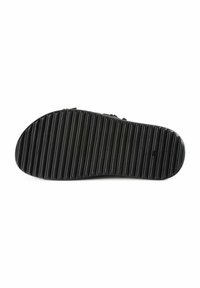 Suela de zapato de goma negra con un patrón texturizado y acanalado, y punta redondeada. Presenta un detalle del logotipo central debajo del área del arco.
