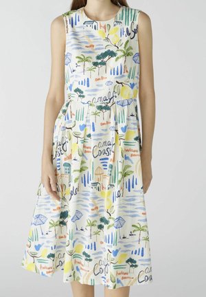 Robe sans manches longueur genou avec imprimé coloré de la côte amalfitaine comprenant des arbres, des parasols, des bâtiments et du texte manuscrit.