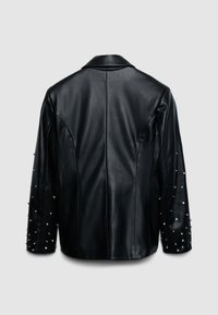 Veste en cuir noir avec un design structuré, des coutures d'épaule prononcées et des détails cloutés sur les manches. Texture lisse sur toute la surface.