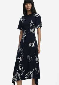 Knielanges navy Kleid mit kurzen Ärmeln, das mit weißen Blumenmustern verziert ist, einer taillierten Taille und einem asymmetrischen Saum. Glatte Textur.