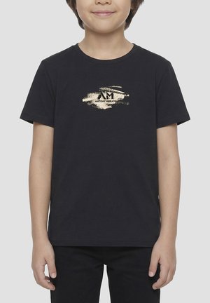 Enfant portant un t-shirt noir avec un motif coup de pinceau doré et le logo "ANTONY MORATO" sur la poitrine, debout les bras détendus.