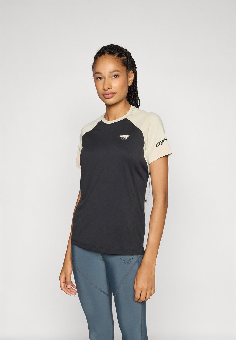 Kortærmet atletisk skjorte med sort krop, beige skuldre, logo på brystet og 'DYNAFIT' tekst på ærmerne. Strækstof, tætsiddende design.