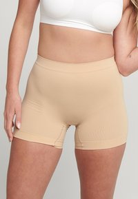 Beige shorts tot halverwege de dijen, gemaakt van een rekbaar, glad materiaal. Heeft een brede, elastische tailleband en vlakke naden voor een naadloze uitstraling.