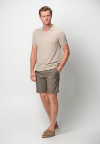 Beige short-sleeve polo shirt, brown linen shorts with pockets, and brown espadrilles. Smooth fabric, relaxed fit.