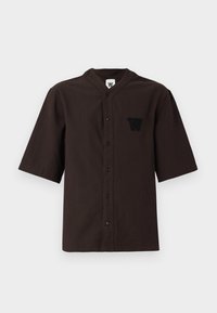 Dark brown short-sleeve shirt featuring a mandarin collar, button closure, and a stitched logo on the left chest pocket. Cotton material, textured.