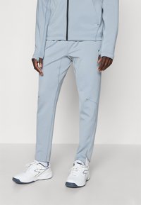 Pantalons de sport bleu clair en tissu lisse, avec une coupe ajustée, des détails de couture subtils et des accents réfléchissants.