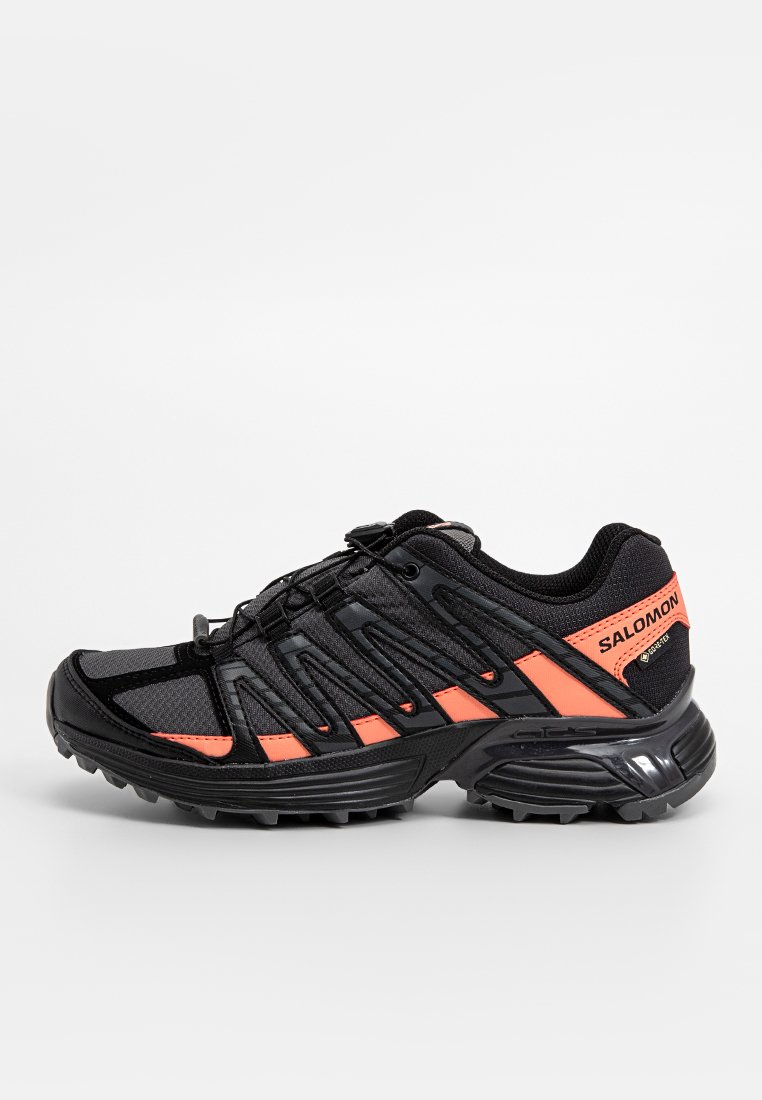 Chaussure de course noire avec des accents orange, tige en mesh, semelle en caoutchouc et système de laçage rapide. Design léger adapté à divers terrains.
