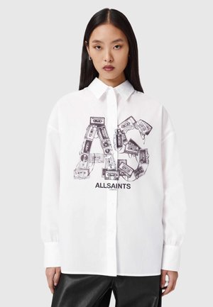 Vit skjorta med knappar som har en grafik av kassettband i en stiliserad arrangemang, med "ALLSAINTS" tryckt nedanför i svart. Slät textur.