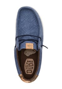 Scarpa in tessuto blu con una superficie strutturata, interni marroni e una etichetta beige. Presenta un accento con motivo camouflage sulla punta e due lacci scuri.