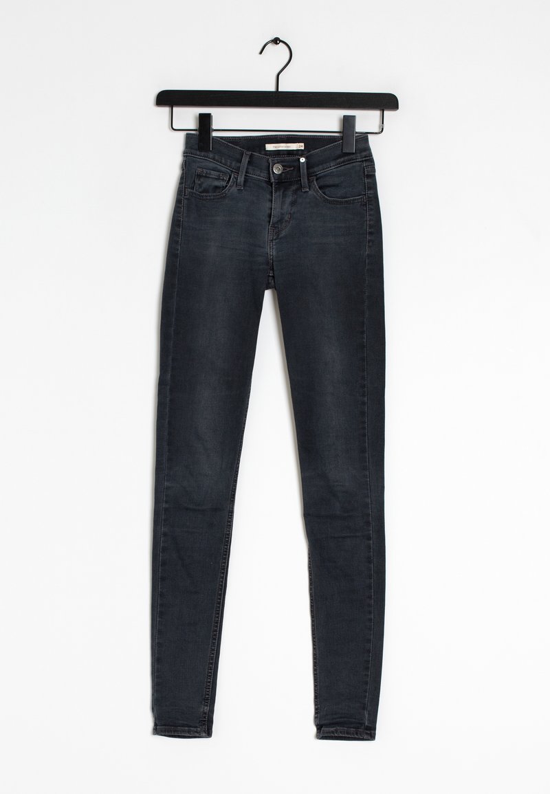 Jean skinny noir en denim, présentant un design classique à cinq poches et des passants de ceinture, suspendu à un cintre en plastique noir.