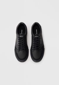 Black sneakers made of leather with a smooth texture, featuring flat laces, reinforced toe caps, and a rubber sole. Simple, minimalist design.