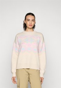 Hellbeige Pullover mit einem pastellfarbenen geometrischen Muster in Rosa und Blau. Verfügt über einen Rundhalsausschnitt und gerippte Bündchen, aus weichem Material gefertigt.