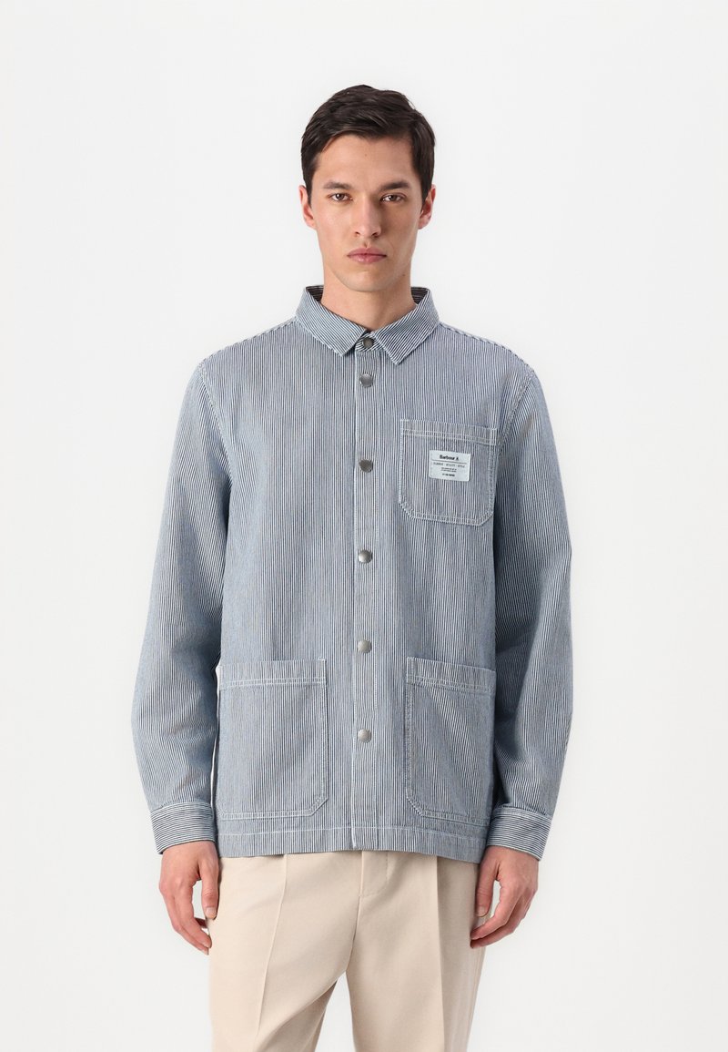 Casaco riscado masculino em azul claro e branco, feito de algodão. Apresenta um fecho frontal com botões, gola e dois bolsos frontais.