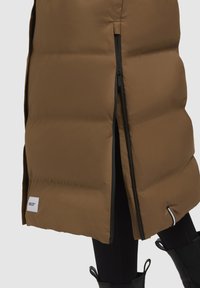Bruine pufferrok van nylon, met zwarte ritssluiting, een split aan de onderkant en een klein logo-label bij de zoom.