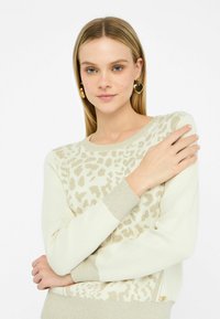 Maglione beige chiaro con stampa leopardata, polsini a contrasto in tessuto testurizzato e vestibilità rilassata. Materiale morbido; presenta un piccolo dettaglio del logo all'orlo.