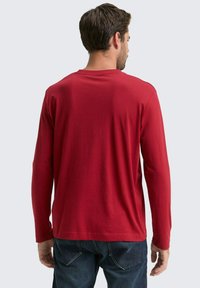 Langärmig rood shirt van zachte stof, met een ronde halslijn en een comfortabele pasvorm. De achterkant toont minimale stikdetails.
