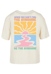 Helles Creme-T-Shirt mit einem bunten grafischen Design eines Sonnensymbols und einem Pfad. Der Text enthält ein motivierendes Zitat in verspielten Schriftarten.