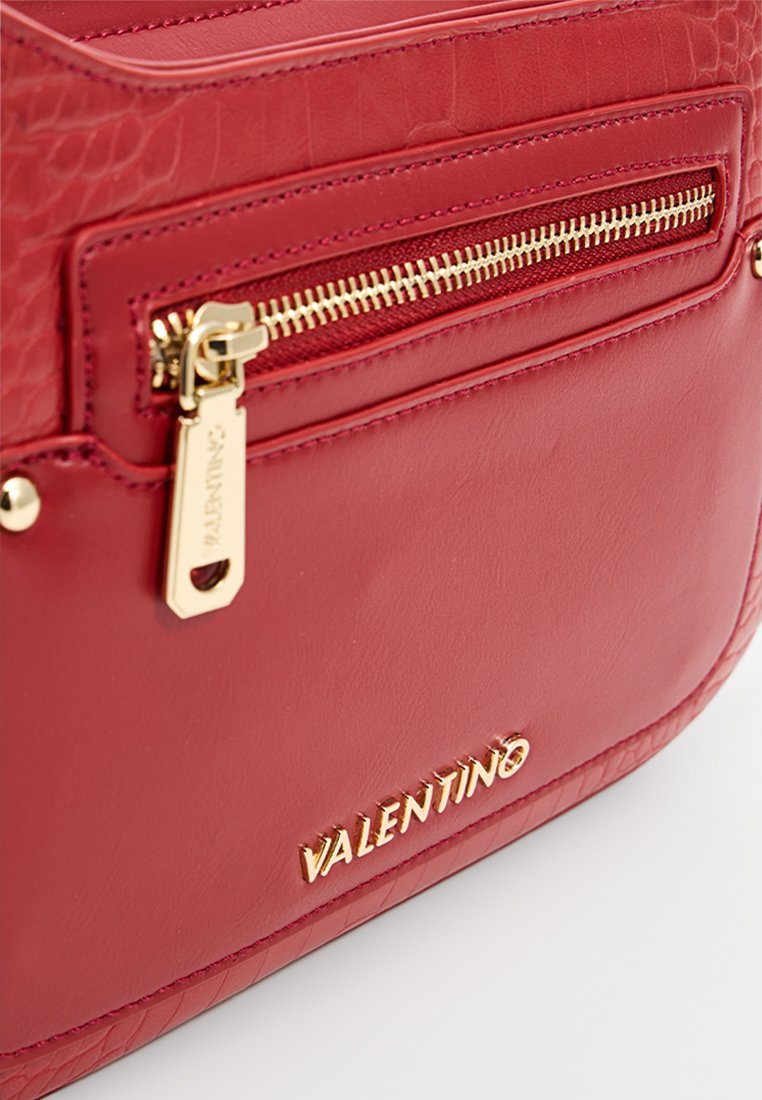 Borsa a tracolla rossa in pelle con dettagli testurizzati, hardware dorato, tasca anteriore con zip e logo impresso sul lato.