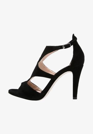 Czarne zamszowe sandały na wysokim obcasie z otwartym palcem, krzyżującymi się paskami i klamrą na kostce. Charakteryzują się eleganckim designem i teksturowanym wykończeniem.