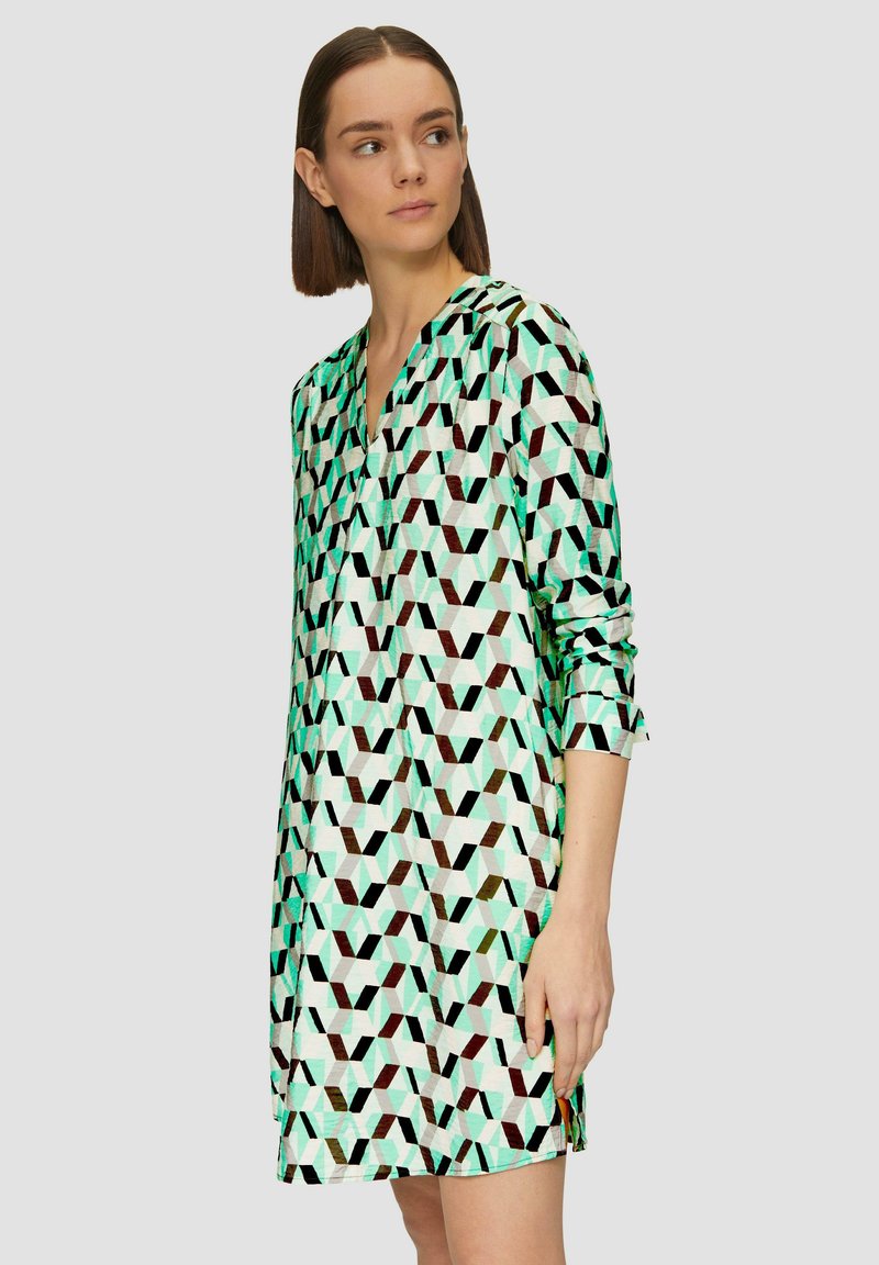 Musterkleid mit geometrischem Design in Mintgrün, Schwarz und Weiß. Lange Ärmel und ein V-Ausschnitt mit lockerer Passform.