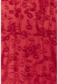 Tissu rouge avec motif imprimé de lèvres texturé, présentant différentes tailles de lèvres éparpillées sur la surface.