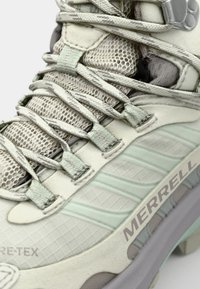 Light gray and mint hiking shoe with mesh panels, textured accents, adjustable laces, and a cushioned sole. Features brand logo on the side.