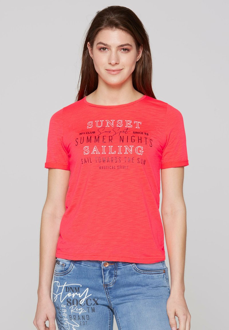 Camiseta corta de manga corta en coral brillante con escote redondo, que presenta texto impreso en diferentes fuentes y colores. Tela suave y ligera.
