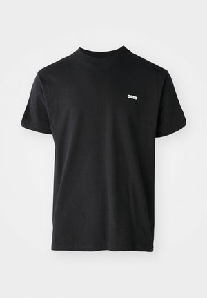 Melnas kreklu ar apaļu kaklu, kas izgatavots no kokvilnas. Uzbūvēts ar mazu baltu "OBEY" logo kreisajā krūšu daļā. Īsas piedurknes un parasts piegriezums.