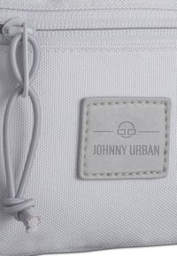 Sacchetto di tessuto grigio con una superficie strutturata, dotato di una cerniera e un'etichetta in pelle goffrata con la scritta "JOHNNY URBAN".