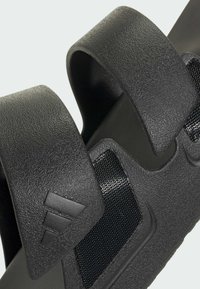 Sorte slip-on sandaler med strukturerede syntetiske remme og en polstret fodseng. Inkluderer mesh-detaljer og et logo i designet.