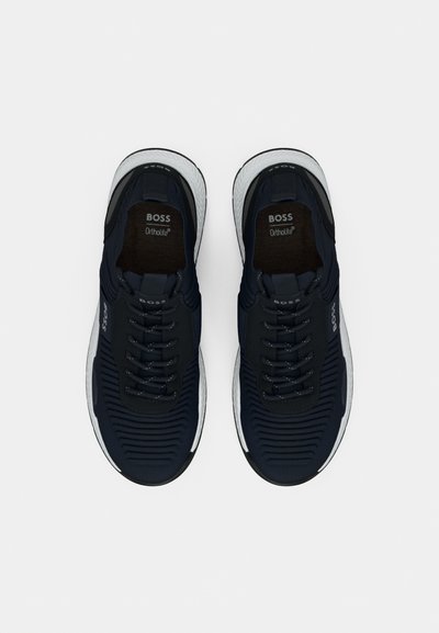 Baskets de sport navy avec une tige texturée, dotées de lacets noirs, d'une semelle blanche et du logo Ortholite sur la languette et la semelle intérieure.