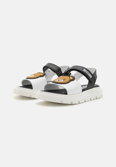 Sandalias en blanco y negro con un diseño moldeado de oso en la parte frontal, suela de goma y correas ajustables para un buen ajuste y comodidad.