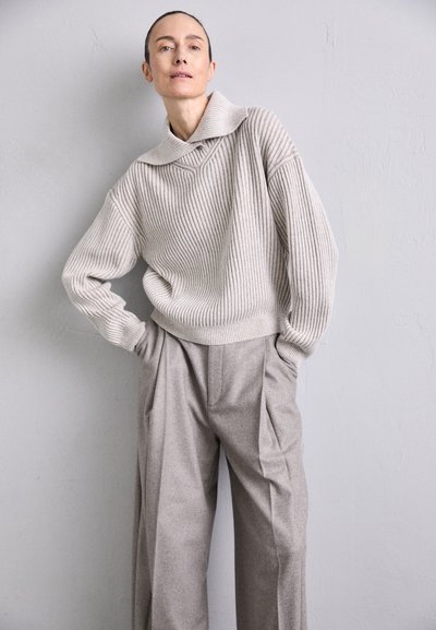 Light gray ribbed sweater with a wide collar, paired with loose-fitting beige trousers. Soft texture, relaxed silhouette, minimal detailing.