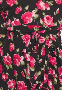 Kukkakuosiset mekko, jossa on musta tausta, suuria vaaleanpunaisia ruusuja ja vihreitä lehtiä. Mekko on vyötäröltä kireä solmimalla, ja siinä on mustia nappeja.