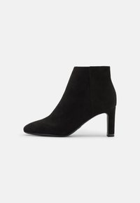 Botas de tobillo de ante negro con punta afilada, tacón delgado y textura suave. Presenta un diseño minimalista y una silueta limpia.