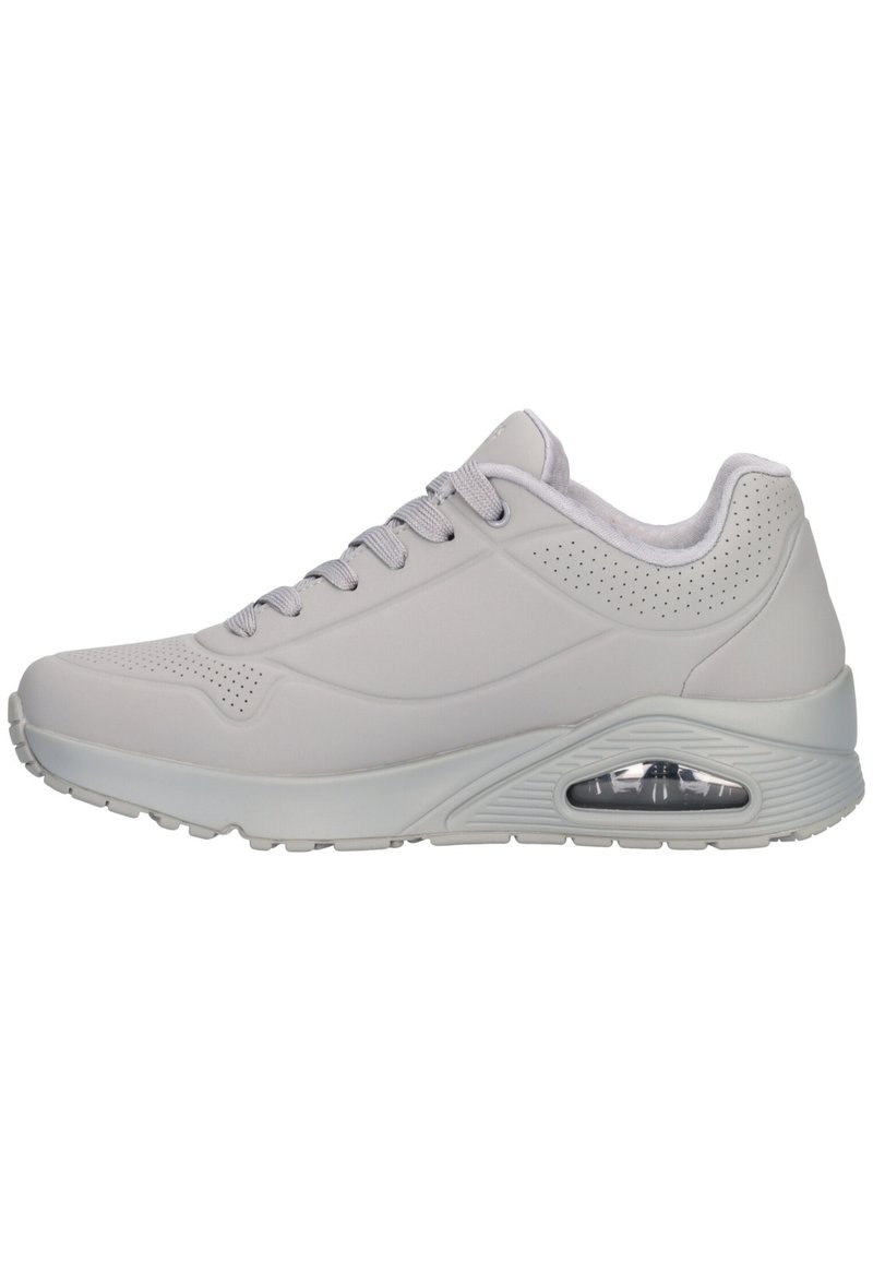Scarpe sportive grigie chiare con tomaia liscia, punta arrotondata, design con lacci, dettagli perforati e un'unità di ammortizzazione visibile nella suola.