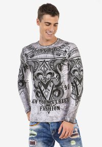 Langärmliges Grafikshirt in Grau mit schwarzen, aufwendigen Designs, darunter Schlangen und Schriftzüge, aus einem glatten Stoff gefertigt.